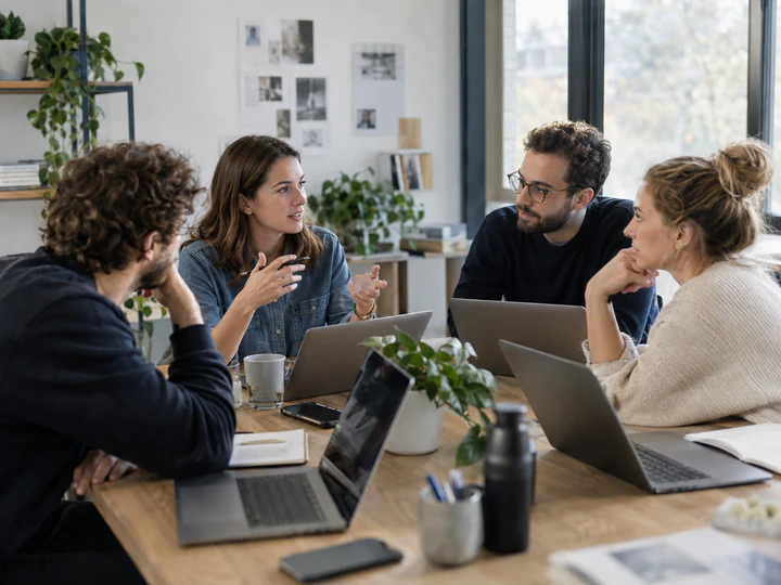 A team collaborating around a table with laptops.